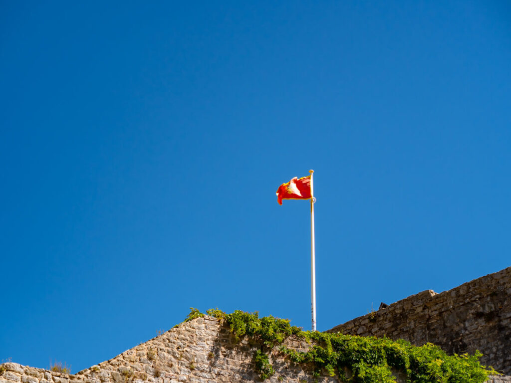 The Montenegro flag flying above a fortress wall.