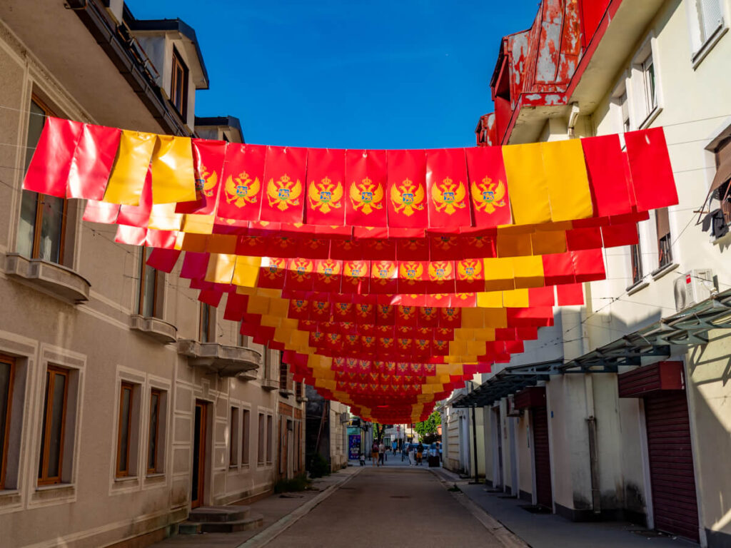 Red and yellow Montenegrin flags strung above a street in Cetinje's historic centre.