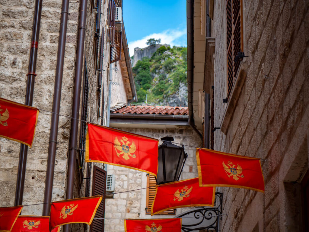 A street in Kotor Old Town decorated with bright red Montenegrin flags.