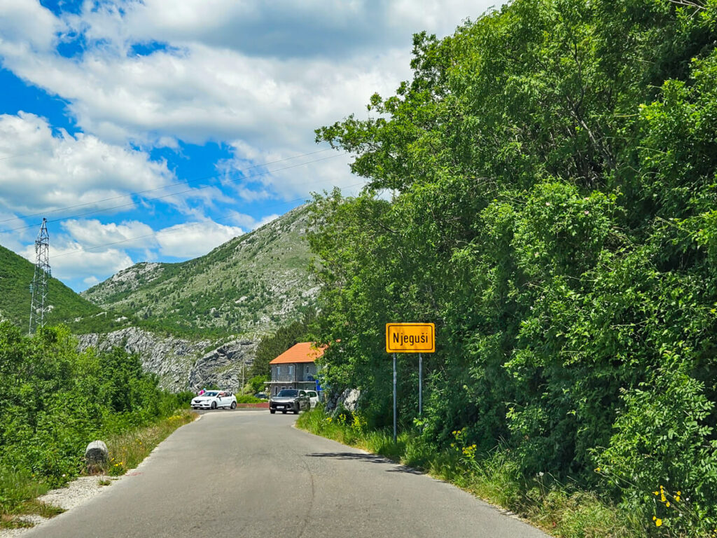 A road leading past a sign indicating the boundary of Njeguši, a small town near Kotor.
