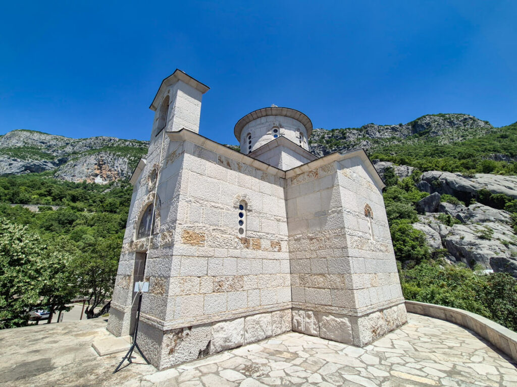 The Church of the Holy Martyr Stanko with a view of Ostrog Monastery in the cliff face in the background,