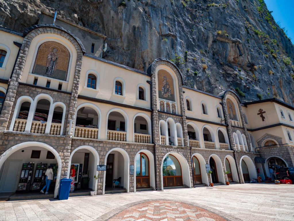 A grand building with stone arches and mosaics housing the gift shop at Ostrog Monastery.