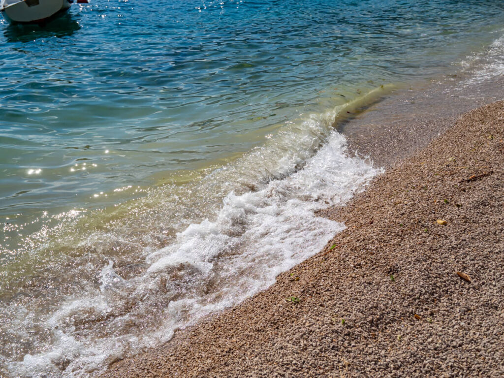 Waves breaking on a sandy shore in Perast, Montenegro.