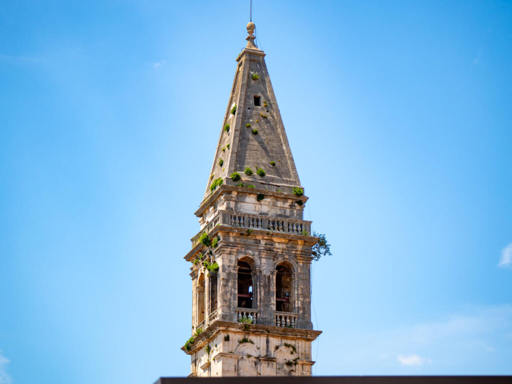 A bell tower of Saint Nicholas Church in Perast against the blue sky.