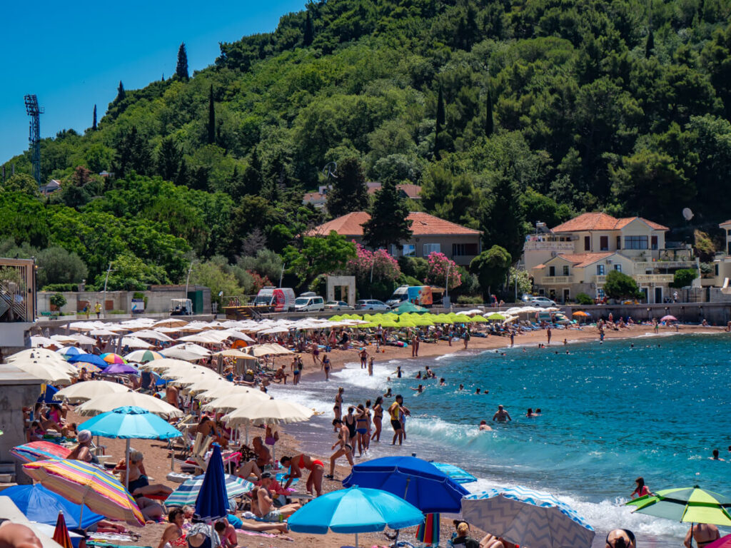 The busy Petrovac Beach, covered in people sunbathing and colourful umbrellas.