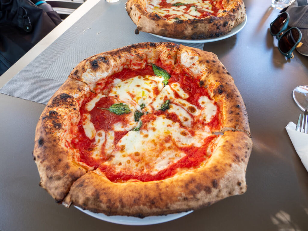 A stonebaked pizza on a plate in Bocalibre Pizza, Perast.