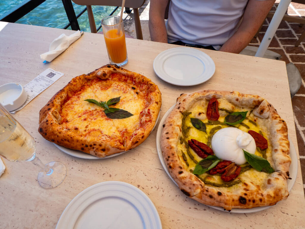 Two plates of pizza on a table in a restaurant in Petrovac.