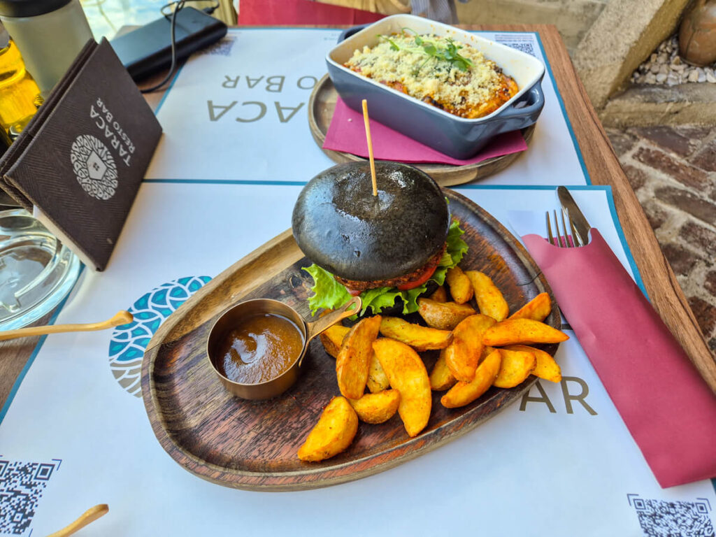 A vegan burger and lasagne on a table in Resto Bar Taraca, a vegetarian-friendly restaurant in Kotor.