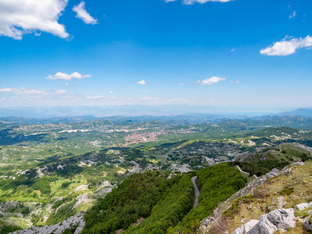 A winding road in Lovćen National Park surrounded by rolling hills and countryside.