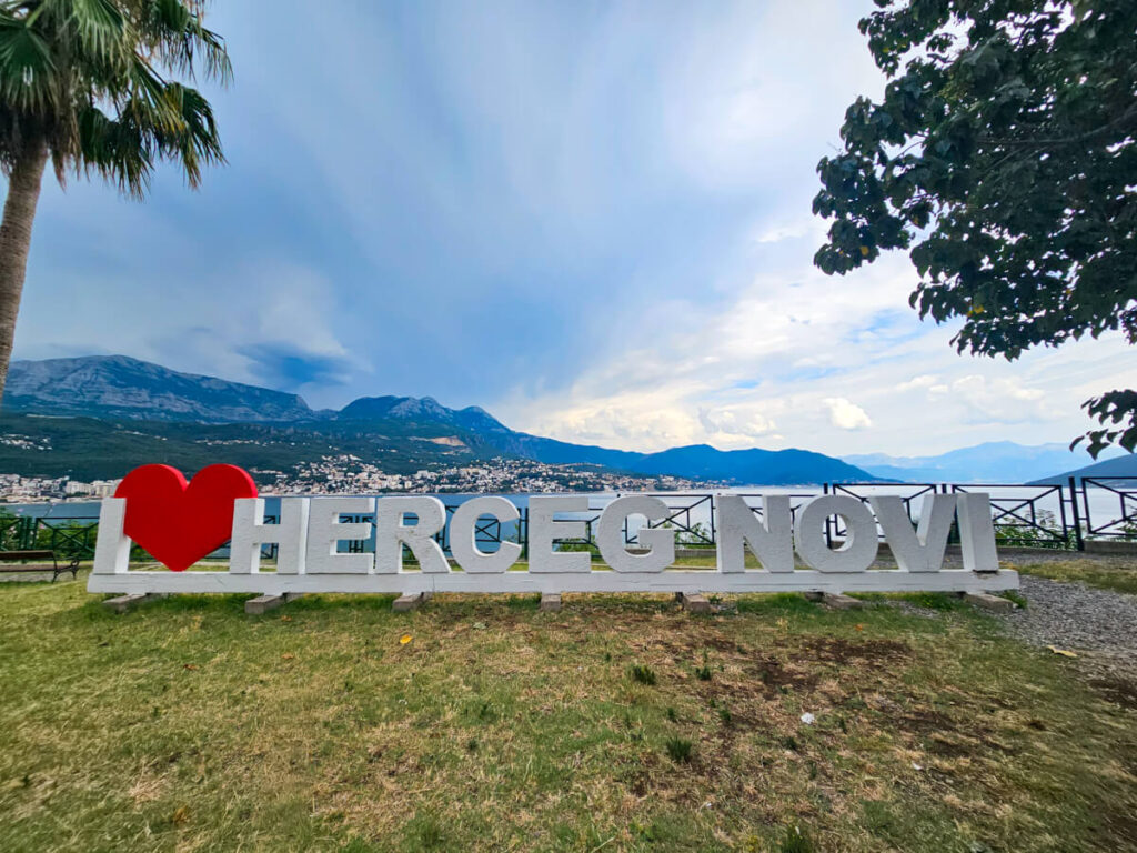 The "I love Herceg Novi" sign, backed by a mountainous coastline.