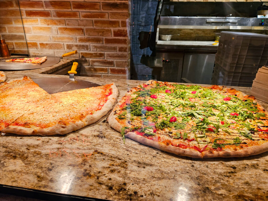 Large pizzas on a counter being sold by the slice in Kotor.