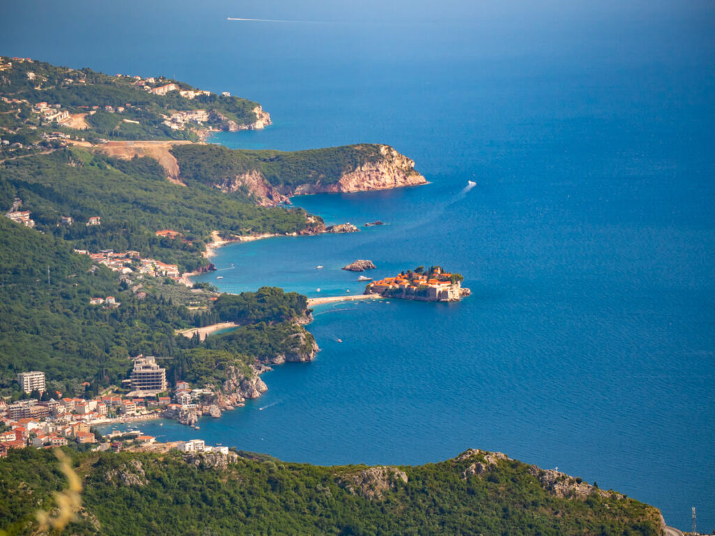 Sveti Stefan Island and town nestled on the coast, viewed from a distance from a roadside viewpoint.