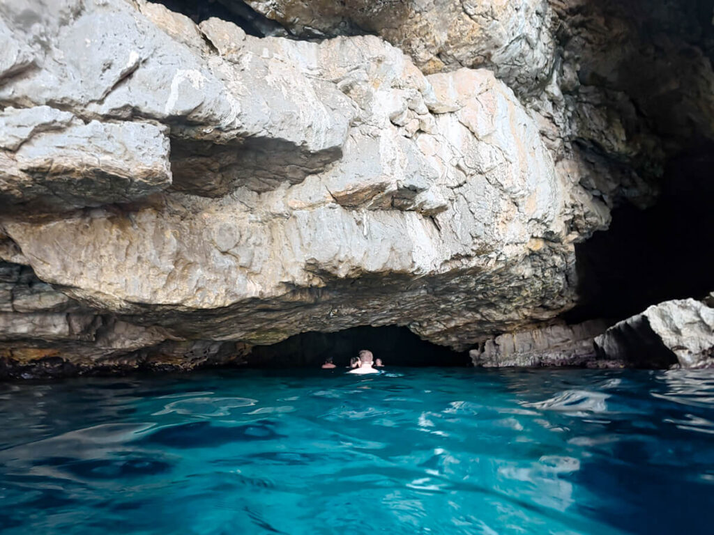 People swimming into a small sea cave near the Blue Cave in Montenegro.