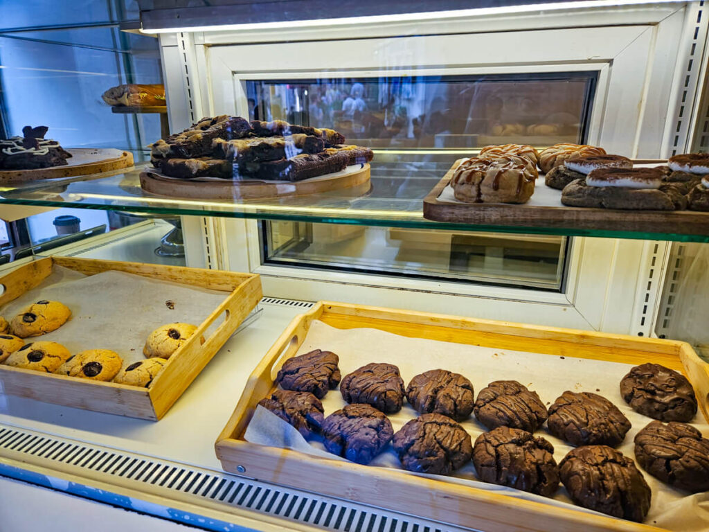 A selection of cookies and cakes in a cabinet in Too Hot to Handle Coffee Shop in Kotor.