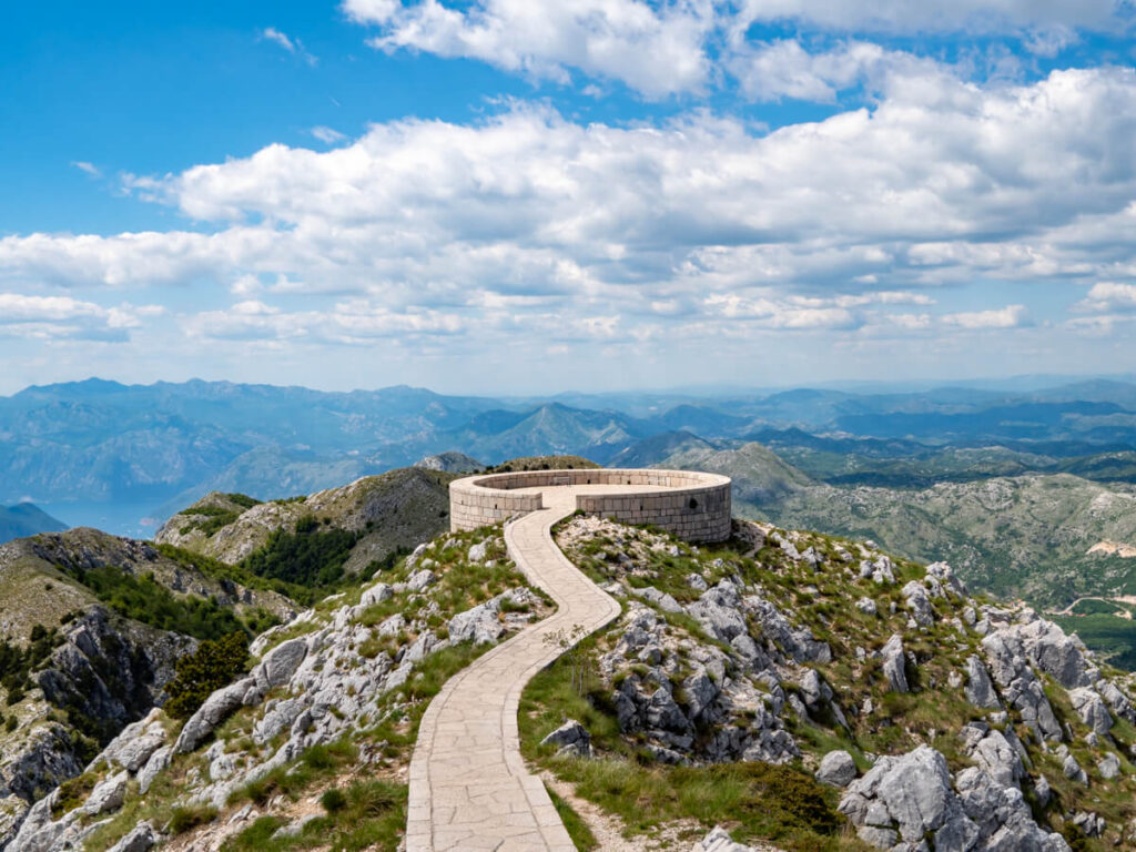 A narrow paved path leading to the circular viewpoint in Lovćen National Park.