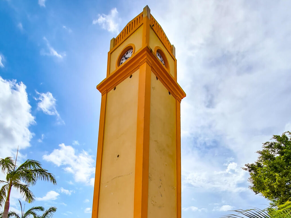 The iconic bright orange clock tower in Benito Juárez Park, a plaza in San Miguel, Cozumel.